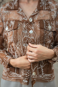 Woman wearing HeenaAgrima's Jaisalmer Jacket, a Brown shirt with white floral embroidery worn by a person