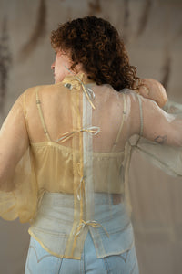 Woman wearing HennaAgrima's Clara Top a sheer top with floral appliqués against a neutral background