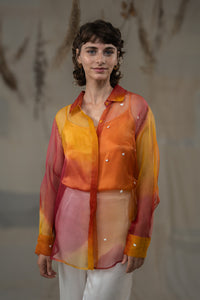 Woman wearing HeenaAgrima's  Cuore w Hearts Shirts a colorful, sheer blouse with a blurred background