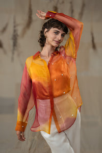Woman wearing HeenaAgrima's  Cuore w Hearts Shirts a colorful, sheer blouse with a blurred background