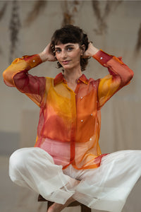 Woman wearing HeenaAgrima's  Cuore w Hearts Shirts a colorful, sheer blouse with a blurred background