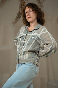 Woman wearing HeenaAgrima's Paddy Linen Jacket, a patterned jacket and light blue jeans against a neutral background. 