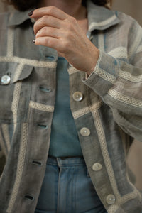 Close up of a person wearing HeenaAgrima's Paddy Linen Jacket, a patterned jacket and light blue jeans against a neutral background