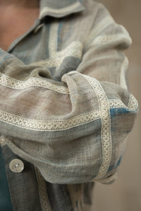 Close-up of a Person wearing HeenaAgrima's Paddy Linen Jacket, a patterned jacket and light blue jeans against a neutral background