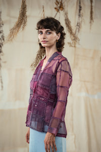 Woman wearing HeenaAgrima's Purple Dream Silk Organza Jacket, a sheer purple jacket over a dark top with light blue jeans against a neutral background