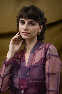 Woman wearing HeenaAgrima's Purple Dream Silk Organza Jacket, a sheer purple jacket over a dark top with light blue jeans against a neutral background