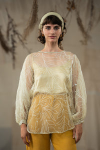 Woman wearing HeenaAgrima's Yellow Eve Silk Organza Top, a sheer top with leaf patterns and yellow pants against a neutral background