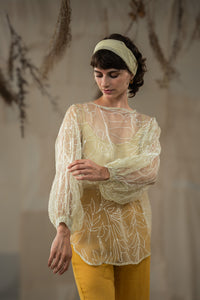 Woman wearing HeenaAgrima's Yellow Eve Silk Organza Top, a sheer top with leaf patterns and yellow pants against a neutral background