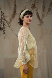 Woman wearing HeenaAgrima's Yellow Eve Silk Organza Top, a sheer top with leaf patterns and yellow pants against a neutral background