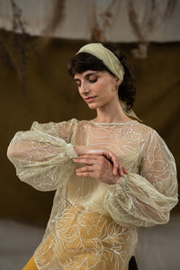 Woman wearing HeenaAgrima's Yellow Eve Silk Organza Top, a sheer top with leaf patterns and yellow pants against a neutral background