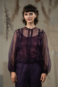 Woman wearing HeenaAgrima's Aubergine Zoe Silk Organza Top, a sheer purple blouse with ruffled details against a neutral background.