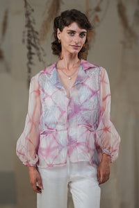 Woman wearing HeenaAgrima's pink quartz shirt, a pastel tie-dye pink shirt with a blurred background