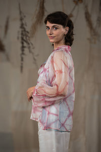 Woman wearing HeenaAgrima's pink quartz shirt, a pastel tie-dye pink shirt with a blurred background