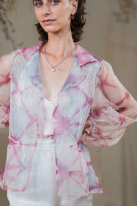 Woman wearing HeenaAgrima's pink quartz shirt, a pastel tie-dye pink shirt with a blurred background