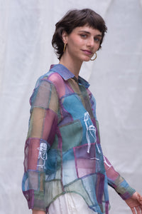 Woman wearing a HeenaAgrima's colorful, patchwork-style shirt, named Stormy against a plain background