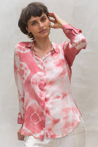 Woman wearing a pink and white naturally tie-dye shirt against a plain background