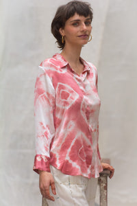 Person wearing a pink and white naturally tie-dye satin silk shirt against a plain background