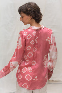 Woman wearing a heenaagrima"s  pink and white naturally tie-dye satin silk shirt against a plain background