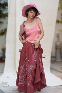 Woman wearing a pink top and maroon skirt with floral patterns, designed by HeenaAgrima, named as red Valen Skirt, holding a plaid bag.