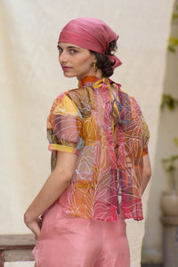 Woman wearing a colorful Indra Fallon Organza Top with a pink turban and skirt against a neutral background