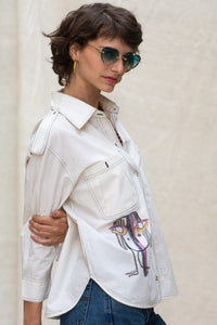 Woman wearing HeenaAgrima's Nina Cotton Shirt, a white shirt with colorful face designs. 