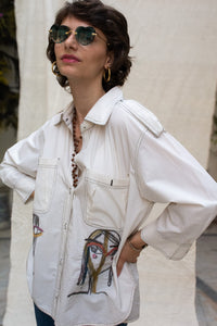 Woman wearing HeenaAgrima's Nina Cotton Shirt, a white shirt with colorful face designs. 