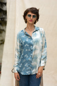 Woman wearing HeenaAgrima's Blu Shibo Stain Silk Shirt, a blue and white patterned shirt with sunglasses and hoop earrings.