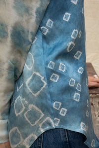 Close-up of a Woman wearing HeenaAgrima's Blu Shibo Stain Silk Shirt, a blue and white patterned shirt with sunglasses and hoop earrings.