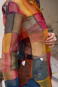 Close-up of a Woman wearing HeenaAGrima's OG Indradhanush Shirt, a colorful patchwork shirt against a white blurred background. 