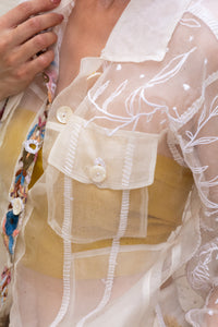 close-up of a floral white jacket, made in organza, named bloom 2.0 by designers HeenaAgrima with a sheer overlay against a neutral background