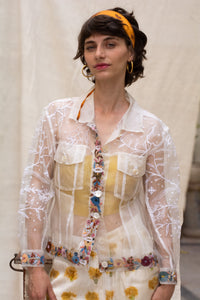 Woman wearing a floral white jacket, made in organza, named bloom 2.0 by designers HeenaAgrima with a sheer overlay against a neutral background