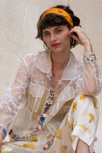 Woman wearing a floral white jacket, made in organza, named bloom 2.0 by designers HeenaAgrima with a sheer overlay against a neutral background