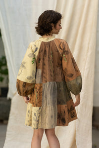 Woman wearing HeenaAgrima's Venus Handloom Cotton Dress patchwork dress with a floral pattern against a draped fabric background