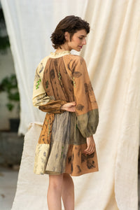 Woman wearing HeenaAgrima's Venus Handloom Cotton Dress patchwork dress with a floral pattern against a draped fabric background