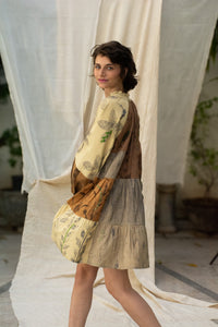 Woman wearing HeenaAgrima's Venus Handloom Cotton Dress patchwork dress with a floral pattern against a draped fabric background