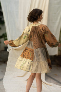 Woman wearing HeenaAgrima's Venus Handloom Cotton Dress patchwork dress with a floral pattern against a draped fabric background