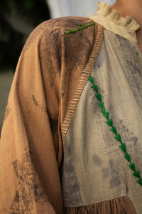 Close-uo of a Woman wearing HeenaAgrima's Venus Handloom Cotton Dress patchwork dress with a floral pattern against a draped fabric background