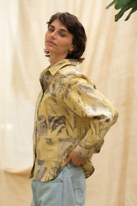 Woman wearing HeenaAgrima's  dessert shirt, a yellow patchwork shirt with a neutral background