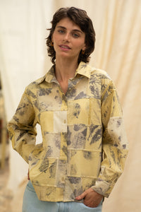 Woman wearing HeenaAgrima's  dessert shirt, a yellow patchwork shirt with a neutral background