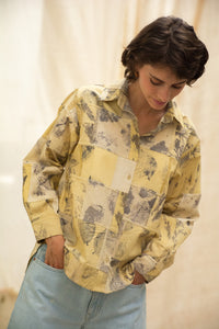 Woman wearing HeenaAgrima's  dessert shirt, a yellow patchwork shirt with a neutral background. 
