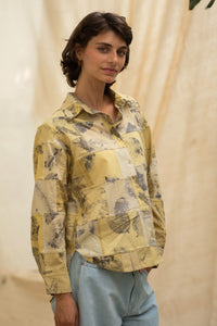 Woman wearing HeenaAgrima's  dessert shirt, a yellow patchwork shirt with a neutral background