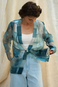 Woman wearing and checking out her HeenaAgrima's Blu Dream Jacket, a blue patchwork organza jacket against a neutral blurred background