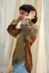 Woman wearing HeenaAgrima Eath linen Shirt, a patterned shirt and light, dyed with iron, cutch, and myrobalan against a neutral background. 