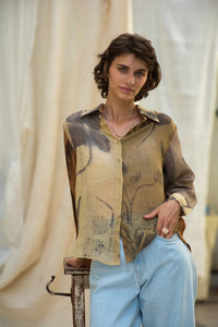 Woman wearing HeenaAgrima Eath linen Shirt, a patterned shirt and light, dyed with iron, cutch, and myrobalan against a neutral background. 