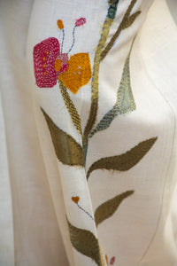 Close-up of a Woman wearing HeenaAgrima's Garden pants, white pants with floral patterns, standing against a neutral background.