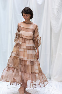 Woman Wearing HeenaAgrima's Mocha Dress, a Sheer, tiered dress with a brown and beige color scheme on a white background. 