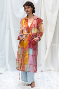 Woman wearing HeenaAgrima's Indradhanush Trench Coat, a colorful, sheer patchwork coat over a white background. 