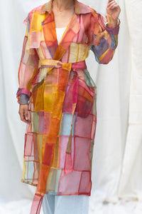 Woman wearing HeenaAgrima's Indradhanush Trench Coat, a colorful, sheer patchwork coat over a white background. 