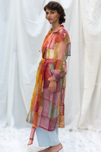 Woman wearing HeenaAgrima's Indradhanush Trench Coat, a colorful, sheer patchwork coat over a white background. 