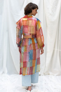 Woman wearing HeenaAgrima's Indradhanush Trench Coat, a colorful, sheer patchwork coat over a white background. 